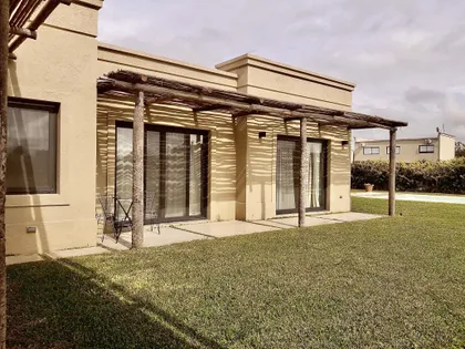 Fachada moderna con pérgola de madera y ventanales grandes frente a jardín — proyecto Santa Teresa Villanueva 2, por Marconi Silva Arquitectos, en Benavidez
