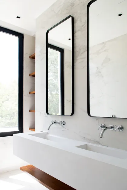 Baño moderno con mármol blanco, vanidad doble y ventanales con vista a la naturaleza — proyecto Bosque Chico, por Estudio Arq. María Sioli, en Garin