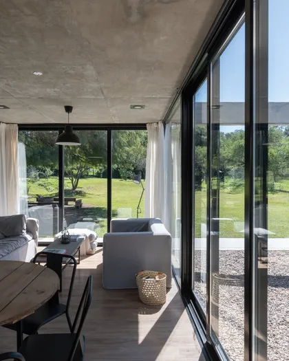 Galería contemporánea con ventanales que se abren al jardín — proyecto Casa SI, por Grupo Studio, en Villa Allende