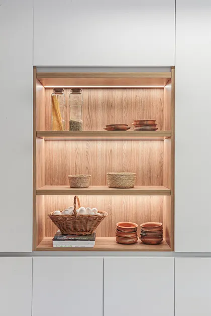 Alacena empotrada con iluminación cálida y vajilla rústica — proyecto Casa Nordelta, por Gutman+Lehrer Arquitectas, en Nordelta