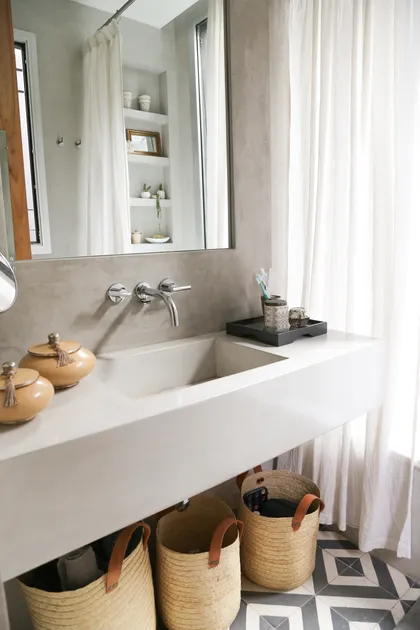Baño moderno con bacha de cemento, paredes de microcemento y canastos de mimbre — proyecto Proyecto San Isidro, por Olivia D, en San Isidro