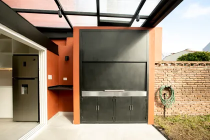 área de parrilla moderna semi-exterior con detalles en ladrillo y metal negro — proyecto Obra Martinez A, por Arq. Lourdes Yarade Saravia, en Martínez