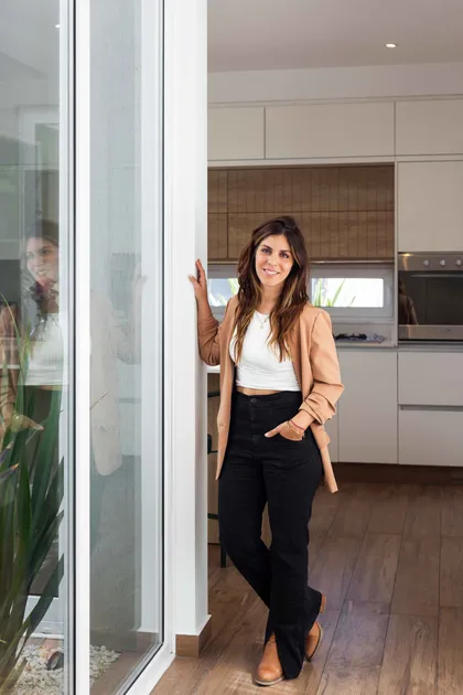 Mujer en sala de estar moderna con ventanal y cocina integrada — proyecto SANTA INÉS I, por Estudio Stepa, en Canning