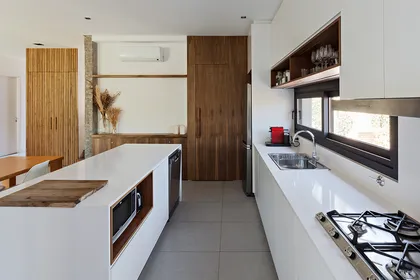 Cocina moderna con isla de cascata y muebles de madera — proyecto CASA RDV, por Rastro Estudio, en San Isidro