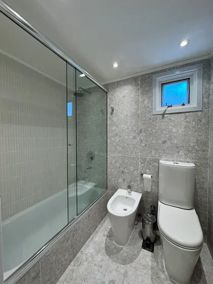 Baño moderno con bidet grande, bañera exenta y paredes de piedra — proyecto Lafinur, por MDBK Arquitectura, en Palermo
