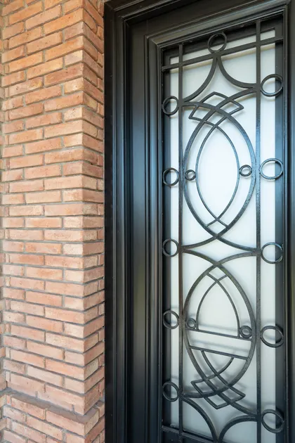 puerta de hierro forjado ornamentada con detalles de ladrillo — proyecto VIVIENDA L.L, por Lorenabusquetsarquitectura, en Córdoba