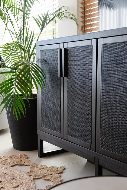 mueble de rattan oscuro con palmera y alfombra floral — proyecto Proyecto Gaby P. , por LINEA NETA diseño interior , en Canning