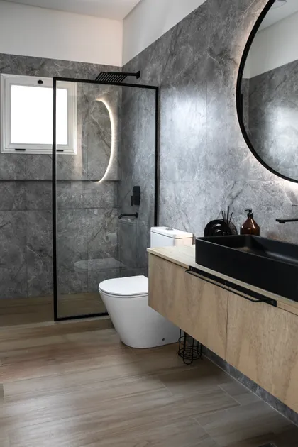 Baño moderno con paredes de mármol, tocador flotante y ducha de vidrio — proyecto Obra El Encuentro, por Arq. Lourdes Yarade Saravia, en Benavidez