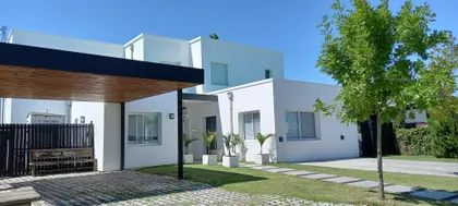 Fachada moderna de casa blanca con pérgola de madera y jardín — proyecto Obra Fachada Nicole, por Arq. Lourdes Yarade Saravia, en Manzanares