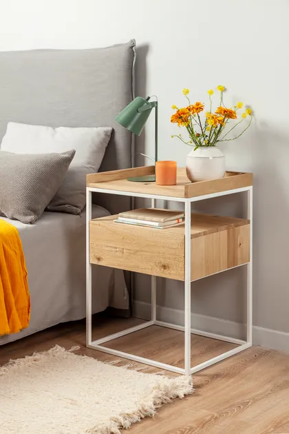 Mesita de noche de madera y metal con cama gris y flores amarillas — proyecto Mesas de luz, por ALTORANCHO, en San Isidro