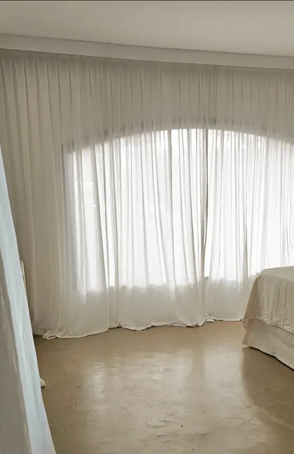 Dormitorio minimalista con ventana arqueada y cortinas blancas — proyecto Fatima , por Claraboia , en Pilar