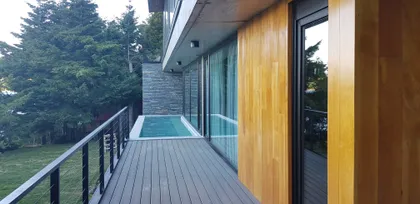 Terraza moderna con piscina integrada y revestimiento de madera — proyecto Casa Península San Pedro, por Servente Larrazabal Arq, en Bariloche