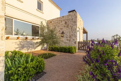 fachada rústica moderna con piedra, ventanas amplias y vegetación — proyecto Casa MF, por Estudio Junor, en Belén de Escobar