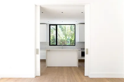 Cocina moderna con isla, muebles blancos y grandes ventanales — proyecto Bosque Chico, por Estudio Arq. María Sioli, en Garin