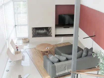 Living moderno de doble altura con chimenea y pared de madera — proyecto Proyecto MH, por Vicky Hurrell, en Mar del Plata