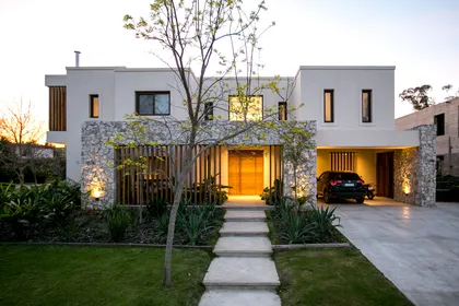 Casa contemporanea blanca con piedra, iluminacion nocturna, jardin frontal — proyecto PGC-01, por VGLA Arquitectos, en General Pacheco