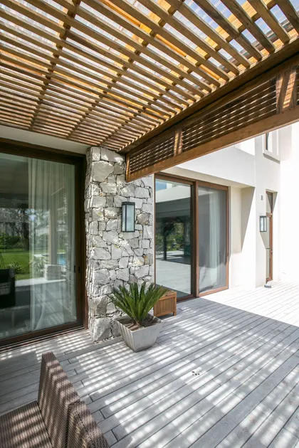 Terraza moderna con pergola de madera, deck gris y acceso vidriera — proyecto PGC-01, por VGLA Arquitectos, en General Pacheco