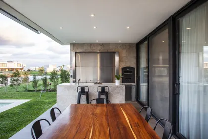 Amplia área de quincho moderna con comedor y cocina exterior — proyecto Casa BJM, por Vanguarda Arquitectos, en Belén de Escobar