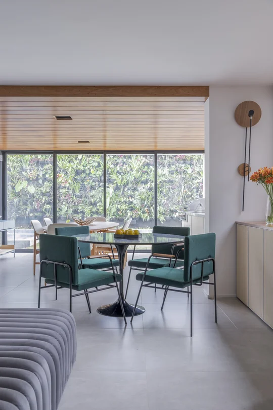 Comedor moderno con mesa redonda y sillas verde jade frente a ventanal — proyecto RLT, por Buriti Arquitetura