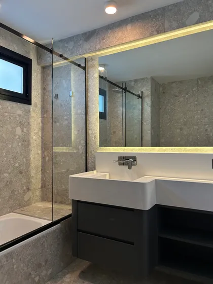 baño moderno con revestimiento de piedra y mueble flotante — proyecto LIBERTADOR II, por ESTUDIO TEZ, en Palermo