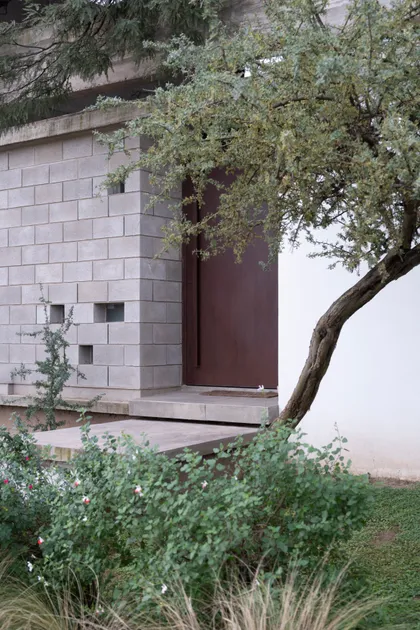 Fachada brutalista con ladrillos de hormigón y puerta metálica — proyecto CASA CHI, por Sol Blanc. arquitecta, en Córdoba
