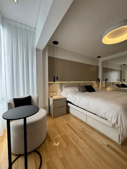 Dormitorio moderno minimalista con cama grande y sillón circular — proyecto Mendoza, por MDBK Arquitectura, en Belgrano