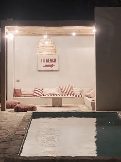 Área de piscina con estilo boho mediterráneo y luces cálidas — proyecto El Refugio, por Grupo Pauta Arquitectura, en Pinamar