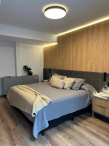 Dormitorio moderno con cabecera tapizada, piso de madera y detalles en tonos naturales — proyecto Casa Oroño, por Estudio Plats, en Buenos Aires