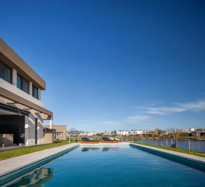Piscina moderna con fachada blanca y cielo azul despejado — proyecto Casa Green, por Frato construcciones , en Belén de Escobar