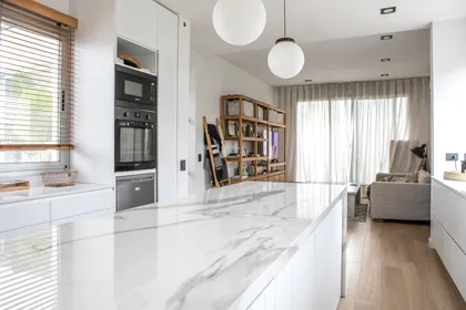 Cocina moderna con isla de mármol y luces colgantes — proyecto Obra El Encuentro, por Arq. Lourdes Yarade Saravia, en Benavidez