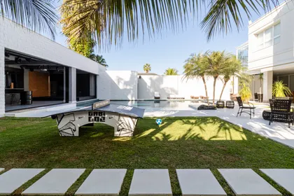 Piscina moderna rodeada de vegetación y deck de madera — proyecto Mansão de Gabigol, por Carlos Pardal, en Guarujá