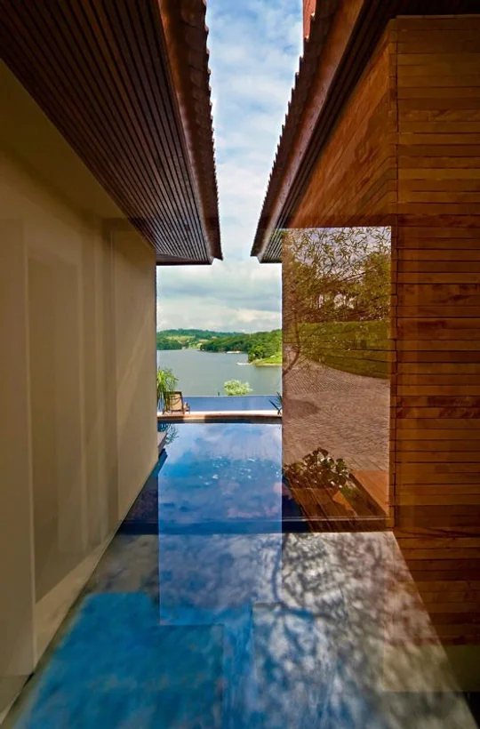 Pasillo moderno con vista a lago, piso espejo azul y madera — proyecto Arquitetura e Interiores I, por Demian Golovaty