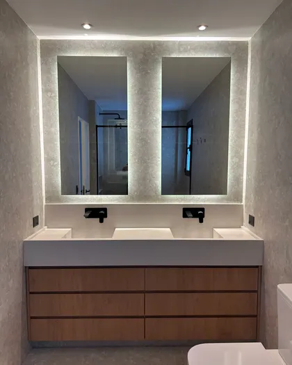 Baño moderno con doble vanitory, espejos retroiluminados y madera natural — proyecto LIBERTADOR II, por ESTUDIO TEZ, en Palermo