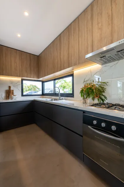 Cocina moderna con muebles de madera y mármol, iluminación indirecta — proyecto Santa Isabel - Andrea Gonzalez, por ABEJA CONCEPT, en Nordelta