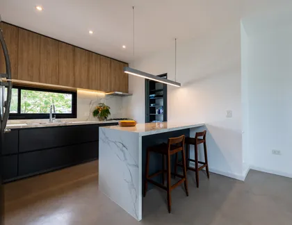 Cocina moderna abierta con isla grande de mármol y detalles en madera — proyecto Santa Isabel - Andrea Gonzalez, por ABEJA CONCEPT, en Nordelta