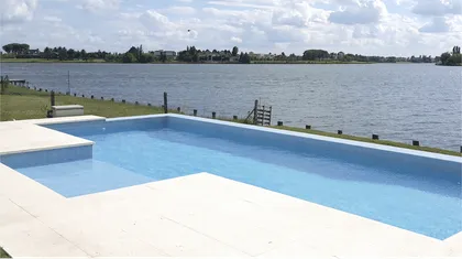 Piscina moderna en lote costero junto a un lago — proyecto CASA NORDELTA, por Alejandra Pan Arquitectura, en Nordelta