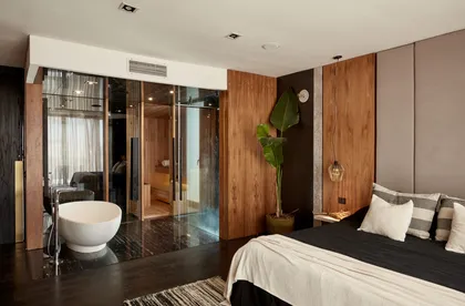 Dormitorio moderno con baño abierto, paredes de madera y luz natural — proyecto El Cantón, por T+T Arquitectos, en El Cantón