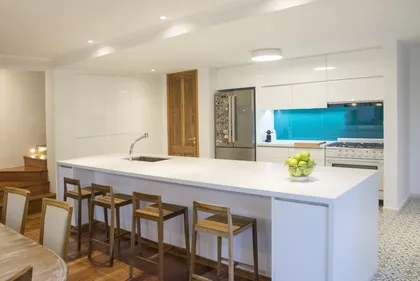 Cocina moderna con isla grande y sillas de madera — proyecto Casa Estilo Francés, por Estudio Fernandez Long & asoc., en Martínez