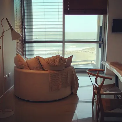 Living moderno con vista al mar, sillón redondo y lámpara de arco — proyecto Departamento MH, por Vicky Hurrell, en Mar del Plata