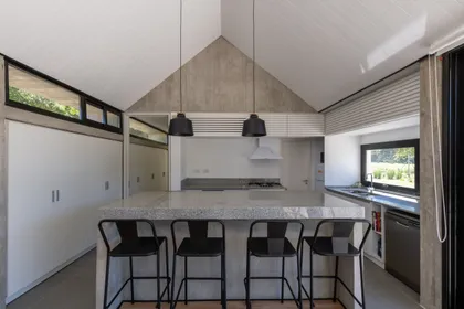 Cocina moderna con isla, techo a dos aguas y pendientes negras — proyecto Casa TT, por Grupo Studio, en Villa Allende