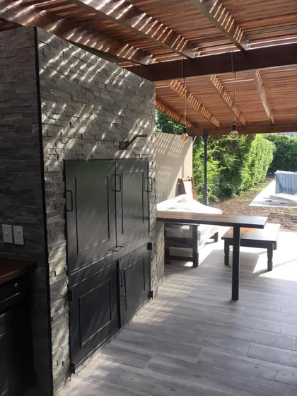 Quincho moderno con pergola de madera, puerta negra y deck gris — proyecto Pilar, por Rioja Arquitectura, en Pilar