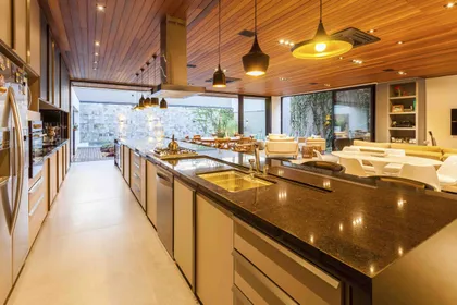 Cocina contemporánea con isla central, mesada negra y techo madera natural — proyecto Casa MaCa, por Studio Jordano Valota