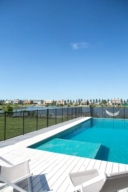 Area de piscina moderna con deck de madera blanco y vista a lago — proyecto San Matias, por ATO Arquitectos, en Barrio San Matías