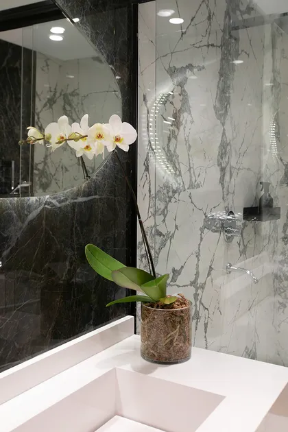 Orquídea blanca en baño moderno con mármol gris y espejo — proyecto Casa Oroño, por Estudio Plats, en Buenos Aires