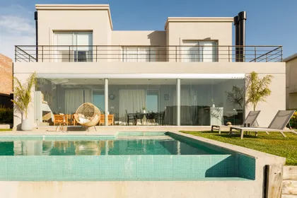 Casa moderna con piscina, muebles de exterior y silla colgante — proyecto TOLDER - CERRAMIENTOS, por Argentina en Obra 2024, en Rincón de Milberg