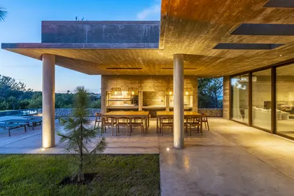 Parrilla moderna con pérgola de hormigón y mobiliario de madera — proyecto CASA sobre el MAR, por Guerrero Arquitectos, en Pinamar