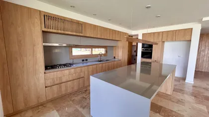 Cocina moderna con isla de madera y mesada de metal — proyecto Casa Puentes, por Guerrero Arquitectos, en Rincón de Milberg
