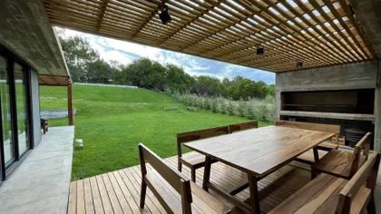 Comedor exterior con deck, pérgola de madera y césped — proyecto Casa R2, por Guerrero Arquitectos, en Pinamar