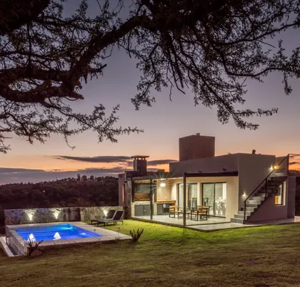 Casa moderna con piscina iluminada al atardecer — proyecto LA CUNKA - POTRERO DE GARAY, por arquiga10573853, en Córdoba
