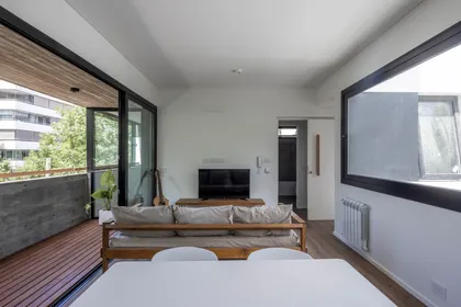 Living moderno con balcón y acabados en madera y hormigón — proyecto Terrazas de Saavedra, por DREI Arquitectura y Desarrollos, en La Plata